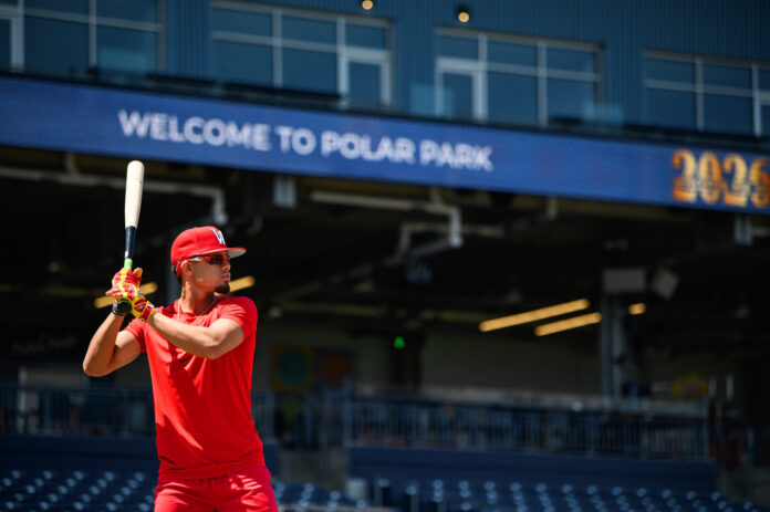 Red Sox top prospect Franklin Arias warms up at Polar Park ahead of his first game with Triple-A Worcester on July 25 2026 Baseball batter in red uniform and cap swings a bat at Polar Park with a blurred blue sign in the background.