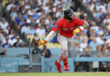 Red Sox Win But Duran’s Tantrum Is a Dealbreaker Baseball player in a red Boston Red Sox uniform runs on the field, helmet on, with a bat on the ground and a blurred crowd in the stands.